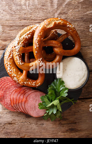 Deutsches Essen: geschnittene Wurst und Brezeln mit Sahnesoße Nahaufnahme auf dem Tisch. vertikale Ansicht von oben Stockfoto