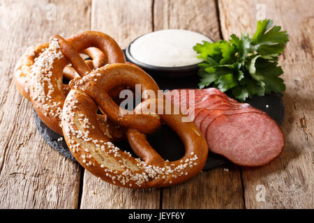 Deutsches Essen: geschnittene Wurst und Brezeln mit Sahnesoße Nahaufnahme auf dem Tisch. Horizontale Stockfoto