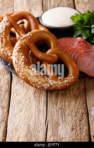 Traditionelle deutsche Brezeln, Würstchen und Sahnesoße Nahaufnahme auf dem Tisch. vertikale Stockfoto