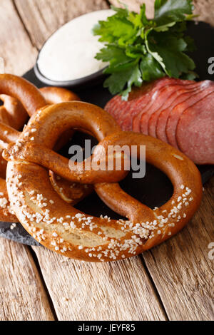 Köstliche hausgemachte Brezeln, in Scheiben geschnittene Wurst und Knoblauch Soße close-up auf dem Tisch. vertikale Stockfoto