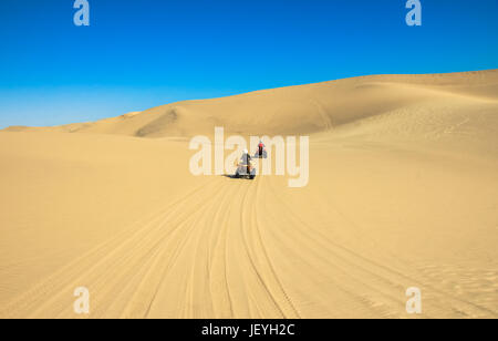 Quad fahren - zwei glückliche Biker im Sand der Wüste. Stockfoto