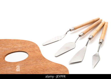 Eine traditionelle hölzerne Palette des Künstlers neben einer Reihe von Spachtel für Ölgemälde.  Isoliert auf weißem Hintergrund mit weichen Schatten beibehalten. Stockfoto