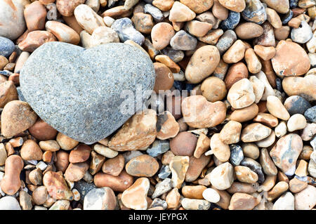 Eine graue herzförmige Stein in der oberen linken Ecke des Rahmens, ruht auf einer Vielzahl von kleineren Steinen.  Querformat (horizontale). Stockfoto