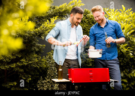 Blick auf zwei junge Männer, die Vorbereitung der Grill im Hof Stockfoto