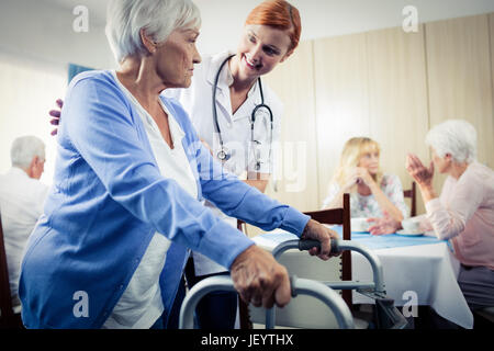 Unterstützung mit einer Gehhilfe Senior Krankenschwester Stockfoto