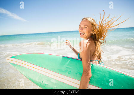 Frau rennt mit Surfbrett am Strand Stockfoto