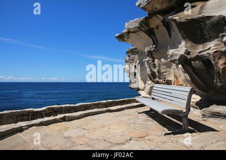 Sitzbank und verwitterter Fels in der Nähe von Bondi Beach Stockfoto