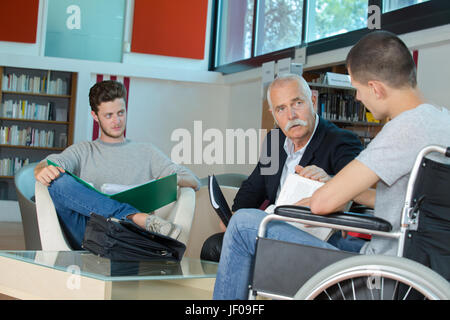 männliche Schüler im Rollstuhl an der Theke in der Universitätsbibliothek Stockfoto