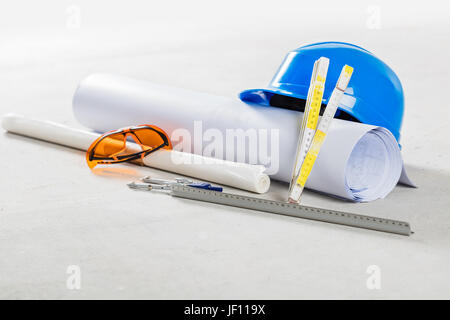 Schutzhelm, Schutzbrille und Baupläne auf der Baustelle. Gebäude und ihre Werkzeuge hautnah. Stockfoto