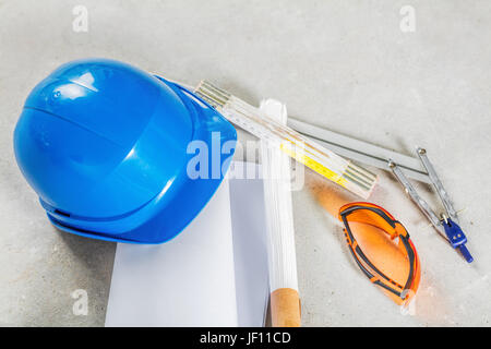 Schutzhelm, Schutzbrille und Baupläne auf der Baustelle. Gebäude und ihre Werkzeuge hautnah. Stockfoto