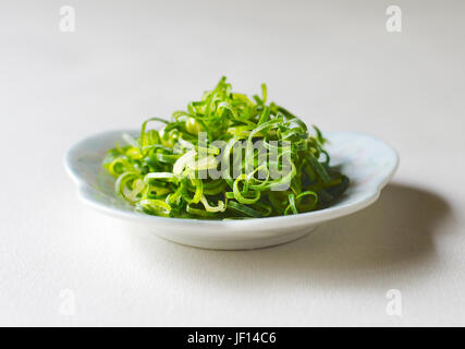 Gehackten Frühlingszwiebeln in eine weiße Schale isoliert auf einem weißen Hintergrund. Stockfoto
