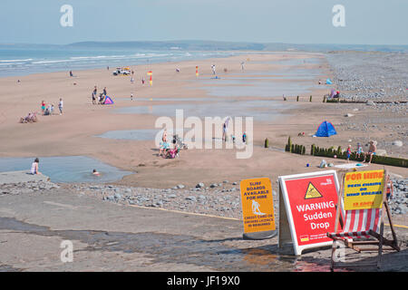 Urlauber genießen den Frühsommer am beliebten Strand von Westward Ho!. Die roten-gelben Flaggen zeigen sicher Baden und Surfreviere Stockfoto