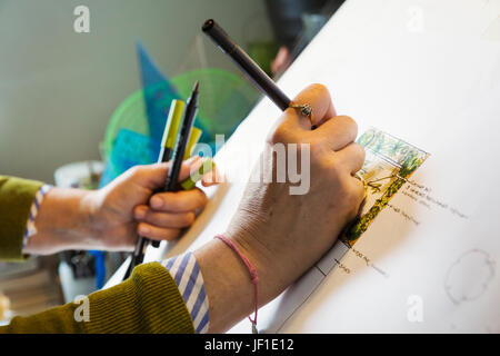 Nahaufnahme von Frau sitzt an einem Zeichenbrett, zeichnen mit einem Fineliner mit einer Entwurfsvorlage. Stockfoto