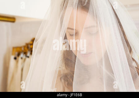 Kopf und Schultern einer Frau, die einem net Brautschleier in einem Fachgeschäft Hochzeit Kleid anprobieren. Stockfoto