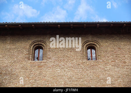 Schlossfenster im mittelalterlichen Stil. Doppelt gewölbte Fenster auf der Fassade der mittelalterlichen Stadtmauer. Biephorum - alte Fenster mit Spalte, alte Architektur-Element der romanischen und gotischen Stil. Stockfoto