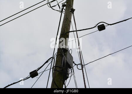 In der Nähe von Strom- und Telefonkabel Kabel auf Holz Holz- Pol mit bedeckt grau bewölkter Himmel im Hintergrund England Großbritannien Stockfoto