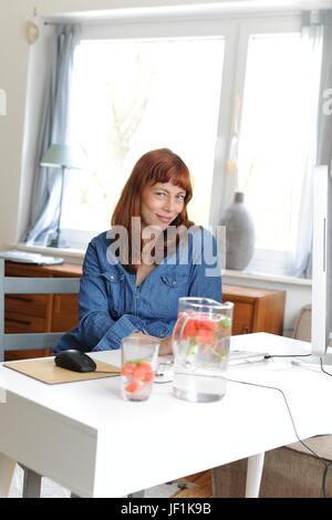 junge berufstätige Frau im home-Office arbeiten. Laptop und Retro Telefon. Stockfoto