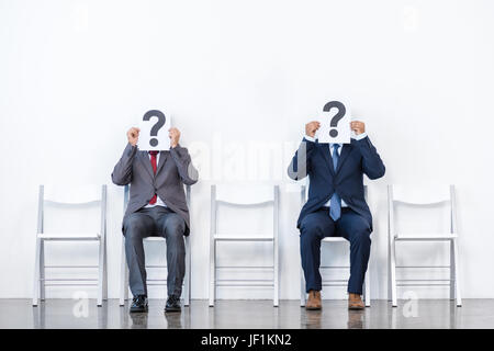 Geschäftsleute in Anzügen sitzen auf Stühlen im weißen Warteraum. Business-meeting Stockfoto