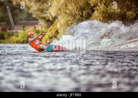 Mann geht für eine Fahrt am Wakeboarden, um Spritzwasser. Stockfoto