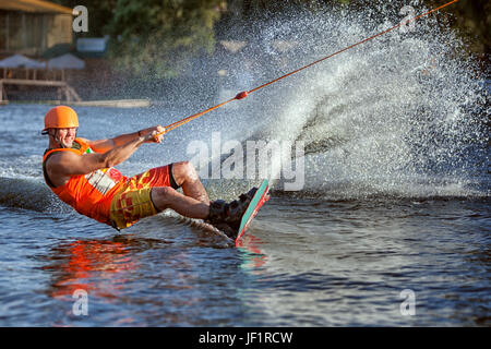 Man gleitet auf dem Brett auf dem See. Er rennt schnell erstellen von Spritzern und Spritzwasser. Stockfoto