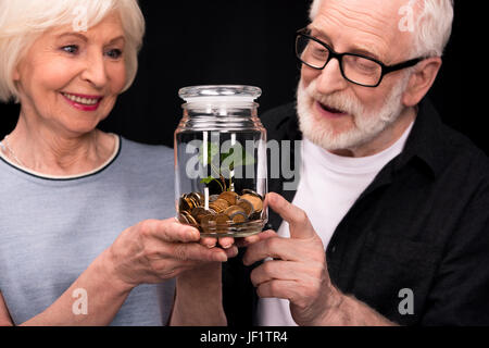 Nahaufnahme von älteres paar stehen zusammen und suchen bei Münzen und Pflanze in Glas Stockfoto