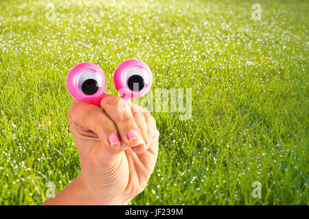 Lustiger Charakter Kreatur suchen sehr überrascht und und versucht, den Betrachter mit weiblichen Hand und Googly Augen auf grasbewachsenen Hintergrund dargestellt einzuschüchtern Stockfoto