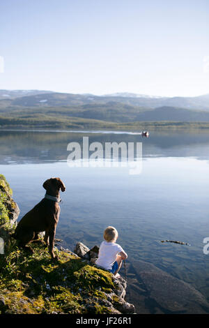 Junge mit Hundesitting an Küste Stockfoto