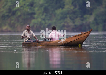 Zwei Männer Fische von hand aus einem kleinen Holzboot an der Quelle des Nils, Jinja, Jinja District, Uganda. Stockfoto