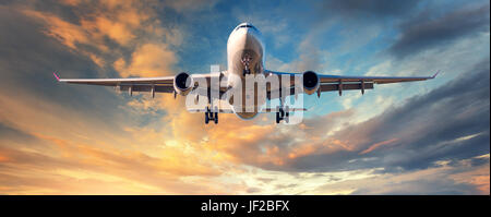 Flugzeug Landung. Landschaft mit weißen Passagierflugzeug fliegt in den blauen Himmel mit Wolken in farbenprächtigen Sonnenuntergang. Hintergrund zu reisen. Passagier airli Stockfoto