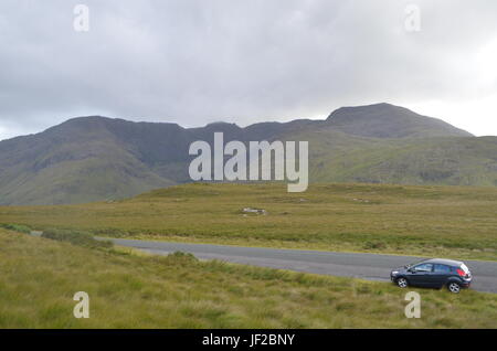 Auto in der Mitte einer Nationalstraße mit Vegetation und Berge in Irland Stockfoto