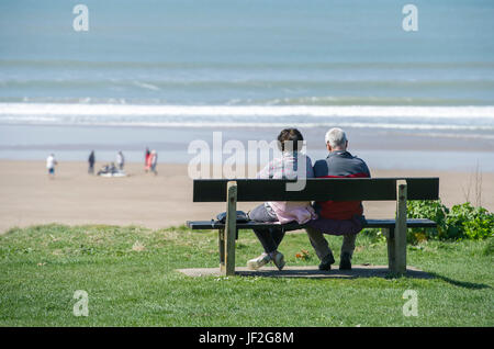 Ältere Paare saßen entspannt und beobachteten das Meer am Woolacombe Beach, Devon Stockfoto