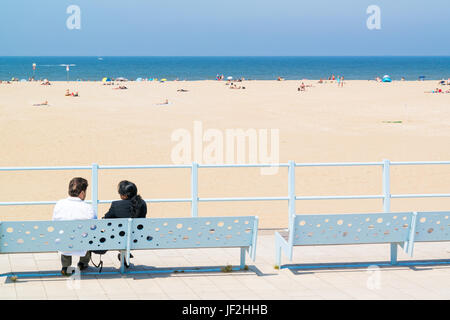 Paar auf Bank am Boulevard Blick auf Strand und Nordsee im Badeort Scheveningen, den Haag, Niederlande Stockfoto