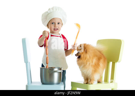 Role-playing Game. Kind junge Koch mit Hund zu spielen. Kind weared Koch versorgt hungrige Welpen. Stockfoto