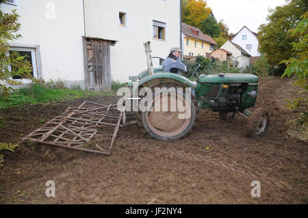 Die Eggen Boden mit alten Traktor Stockfoto