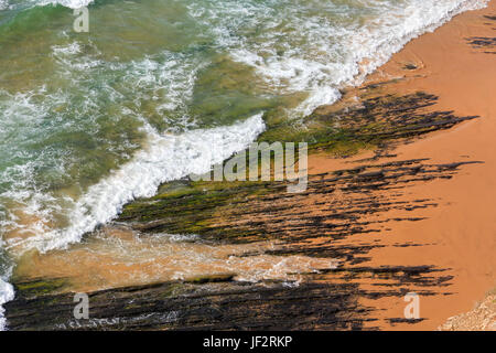 Felsformationen auf Strand und Surf Wave. Stockfoto