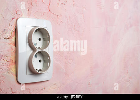 Weiße Buchse auf rosa Wand Stockfoto