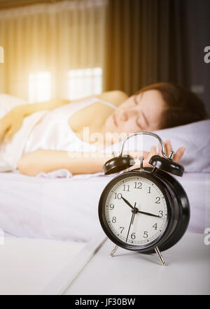 10:00 Uhr anzeigen und Frau schläft auf Bett mit Sonnenlicht am Morgen Stockfoto