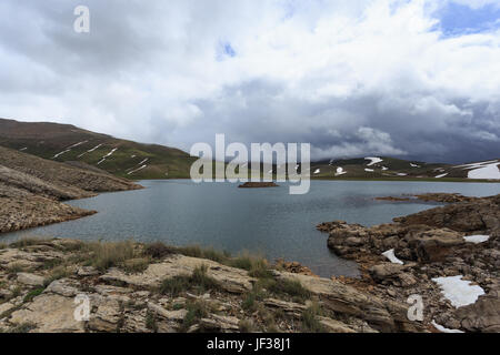 Horizontalen Schuss von Mountain Lake umgeben von Pisten fallenden Schnee schmelzen Stockfoto