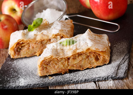 Apfelstrudel, bestreut mit Zucker Pulver Nahaufnahme auf dem Tisch. Horizontale Stockfoto