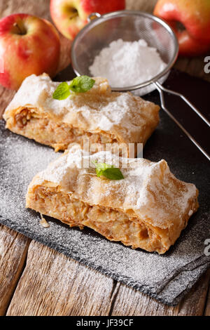 Leckere Stück Apfelstrudel mit Puderzucker und Minze Closeup auf einem Tisch. Vertikal Stockfoto
