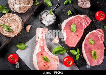 Rohe Bio-Fleisch. Auswahl von mehreren Arten von rotem Fleisch: Schweineschnitzel auf Knochen, Steaks von Schwein und Huhn Schnitzel im Raster von Schweinefett. Mit Zutaten f Stockfoto