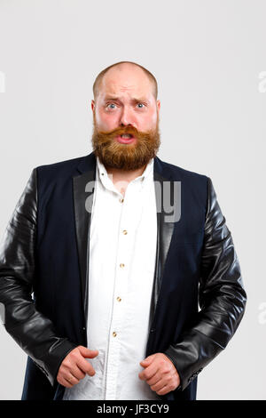 Stirnrunzelnd Mann mit Ingwer Bart in schwarz Jacke auf leeren grauen Hintergrund Stockfoto
