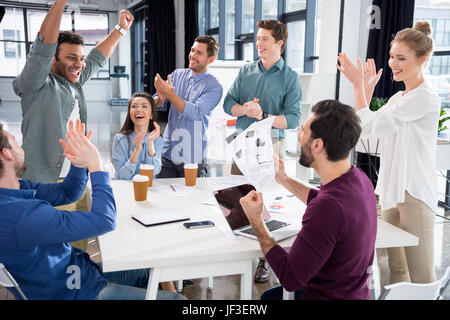 Business-team feiert Erfolg zusammen am Arbeitsplatz im Büro, junge professionelle Gruppenkonzept Stockfoto