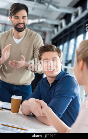 Seitenansicht des Lächelns Geschäftsleute schütteln die Hände auf kleinen Büro treffen Stockfoto