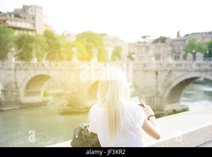 Eine blonde Frau, von hinten gesehen nimmt ein Foto von Castel St'Angelo in Rom an einem Sommertag Stockfoto