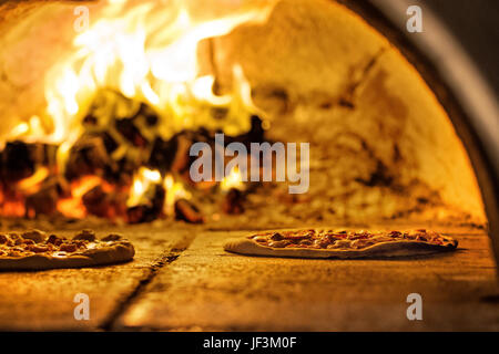 Eine Pizza ist vor einem Holzofen, aus dem es kam Stockfoto