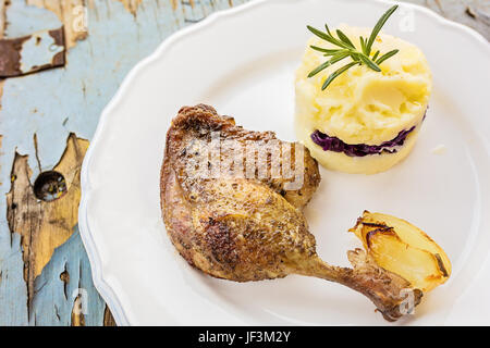 Gebratene Ente mit Kartoffeln und Rosmarin auf einem Holztisch Stockfoto