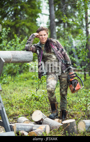 Frau hält Kettensäge und Blick in die Kamera Stockfoto