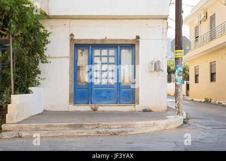 Elounda, Kreta, Griechenland - 12. Juni 2017: Fassade des Hauses in einer Ecke der Straße aufgegeben Windows von Zeitungen abgedeckt Stockfoto