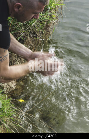 Junge seine Hände waschen in einem See Stockfoto